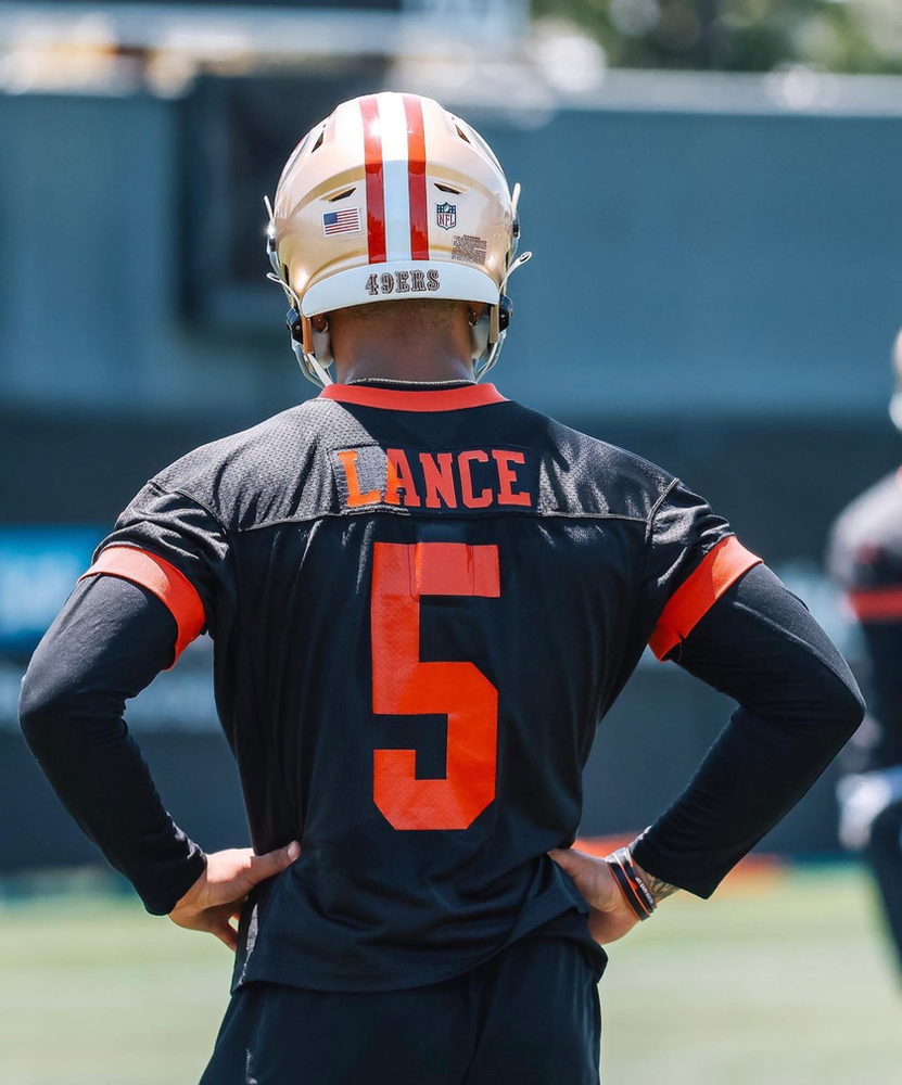 Trey Lance looks on from the sideline 