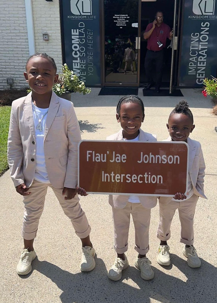 Three young boys holding Flau’Jae Johnson sign commemorating her new highway. 