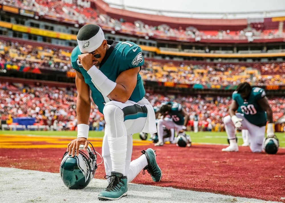 Jalen Hurts prays in end zone 